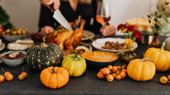 Thanksgiving meal displayed on serving platters on a table with pumpkins and fall floral displays.