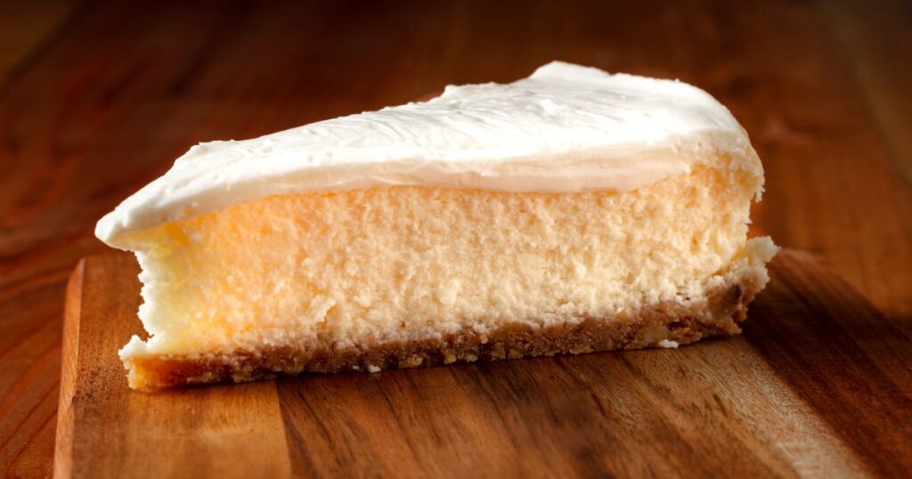 A piece of homemade cheesecake on a wooden board.