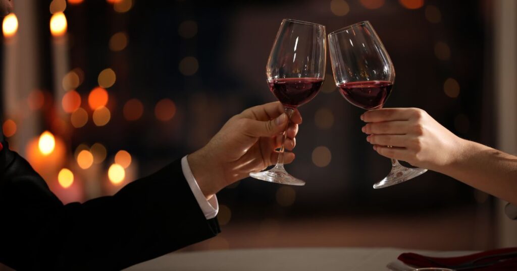 Two hands clinking wine glasses in a romantic atmosphere.