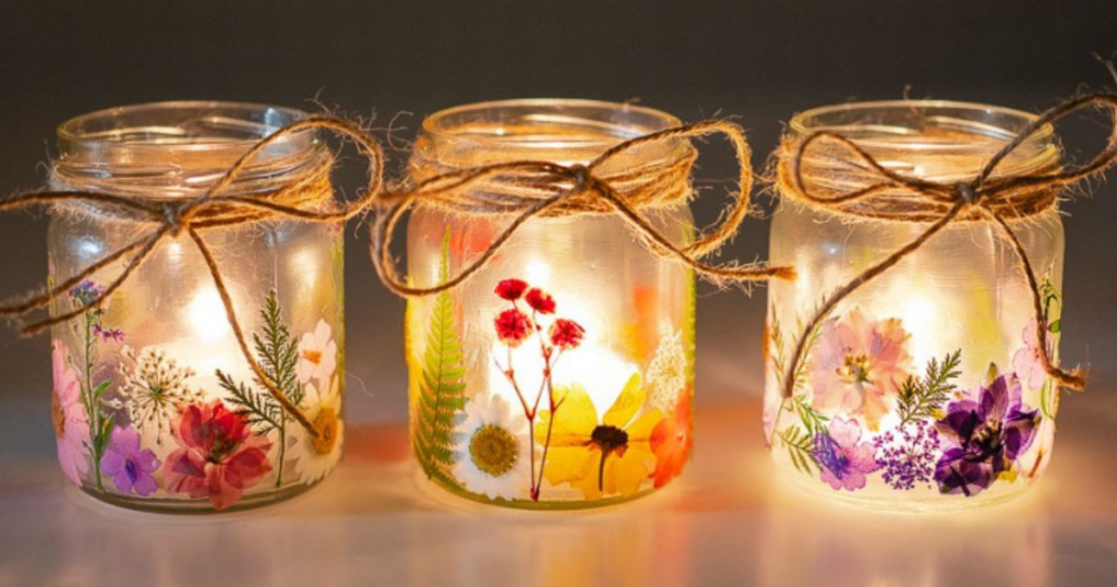 Mason jars with pressed flowers, twine bows, and a candle inside. 