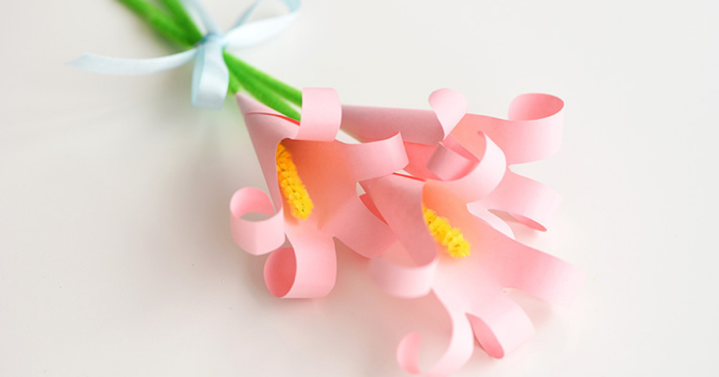 Pink paper flowers with yellow centers and green pipe cleaner stems.