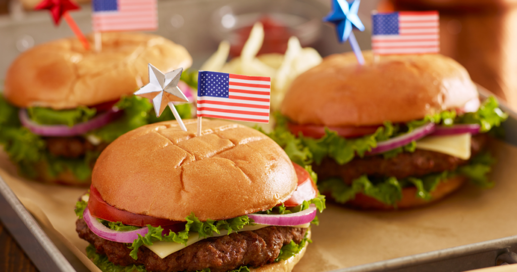 Classic cheeseburgers with American flags on top, and other 4th of July decor.