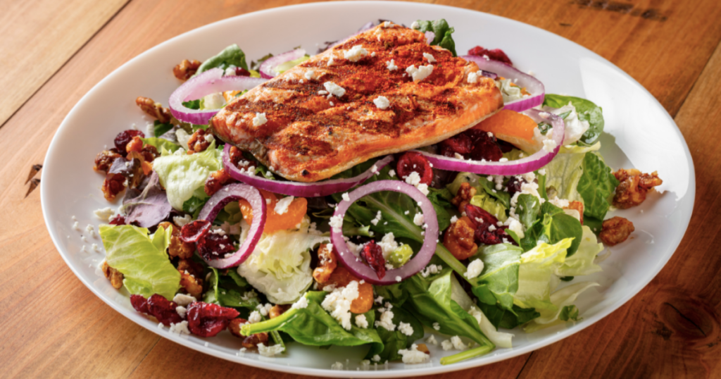 A Grilled Salmon Walnut Salad with fresh fruit, vegetables, and feta. 