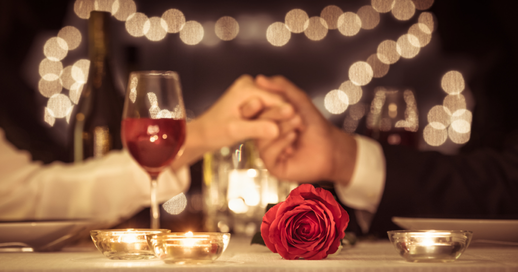 Couple holding hands over Valentine’s Day dinner.
