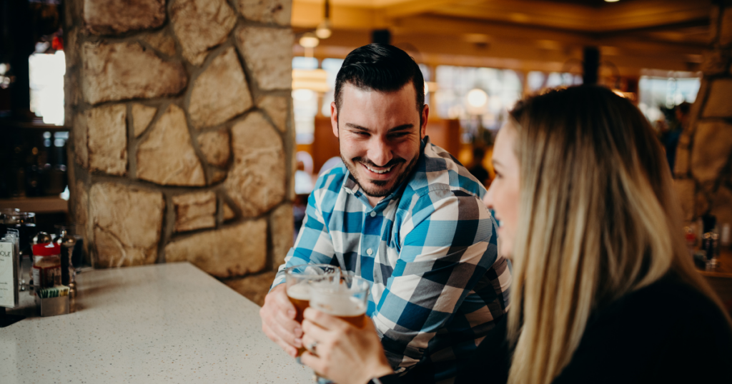 Couple enjoying happy hour in Sacramento at the bar with drinks.